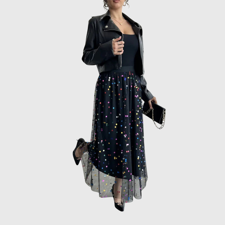 A woman in a black pleated skirt covered in multicoloured sparkling confetti dots, styled for an evening out.