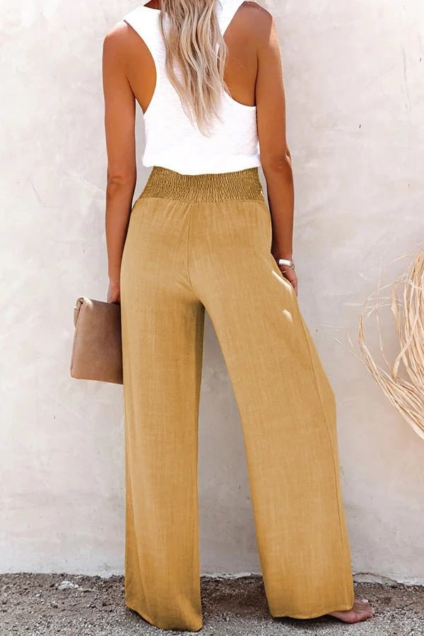 A woman in high-waisted loose wide-leg pants with subtle button detailing, styled for an elegant everyday look.