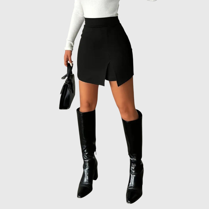 A woman wearing a sleek high-waisted black mini skirt with a front slit.