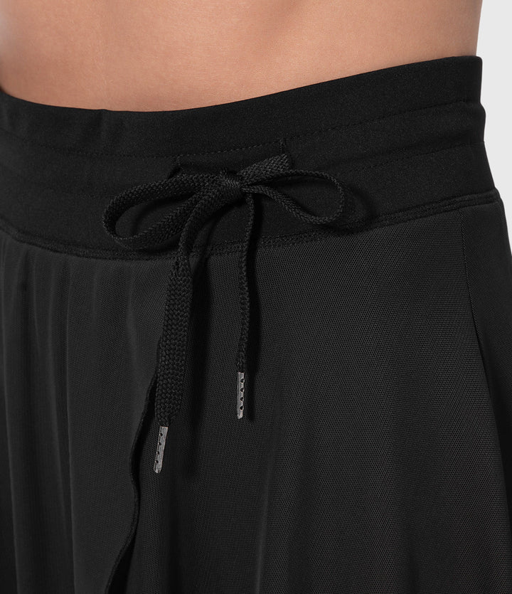 A woman in an elegant high-waisted flowing skirt, styled for a versatile day-to-evening look.