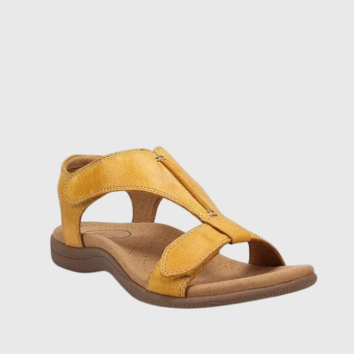 A woman wearing T-strap comfort sandals with a summer dress, looking relaxed and elegant.