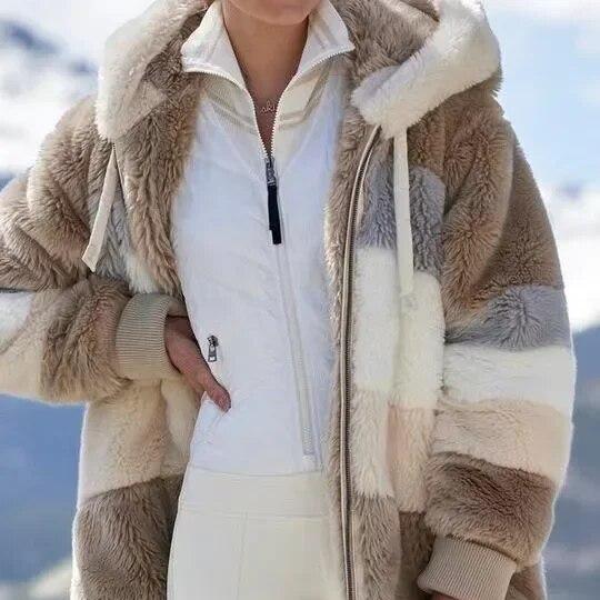 A woman wearing a plush oversized hooded zip jacket in blue and cream colour-block panels.
