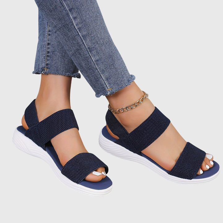 Black open-toe everyday sandals with wide stretch straps and a thick cushioned sole.