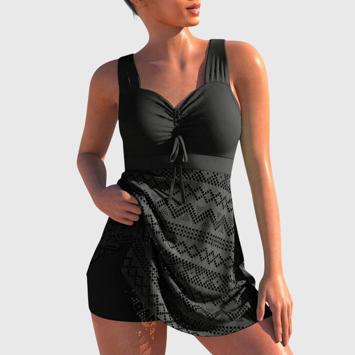 A woman by the sea in a printed two-piece swimsuit with a skirted bottom, relaxed and confident.