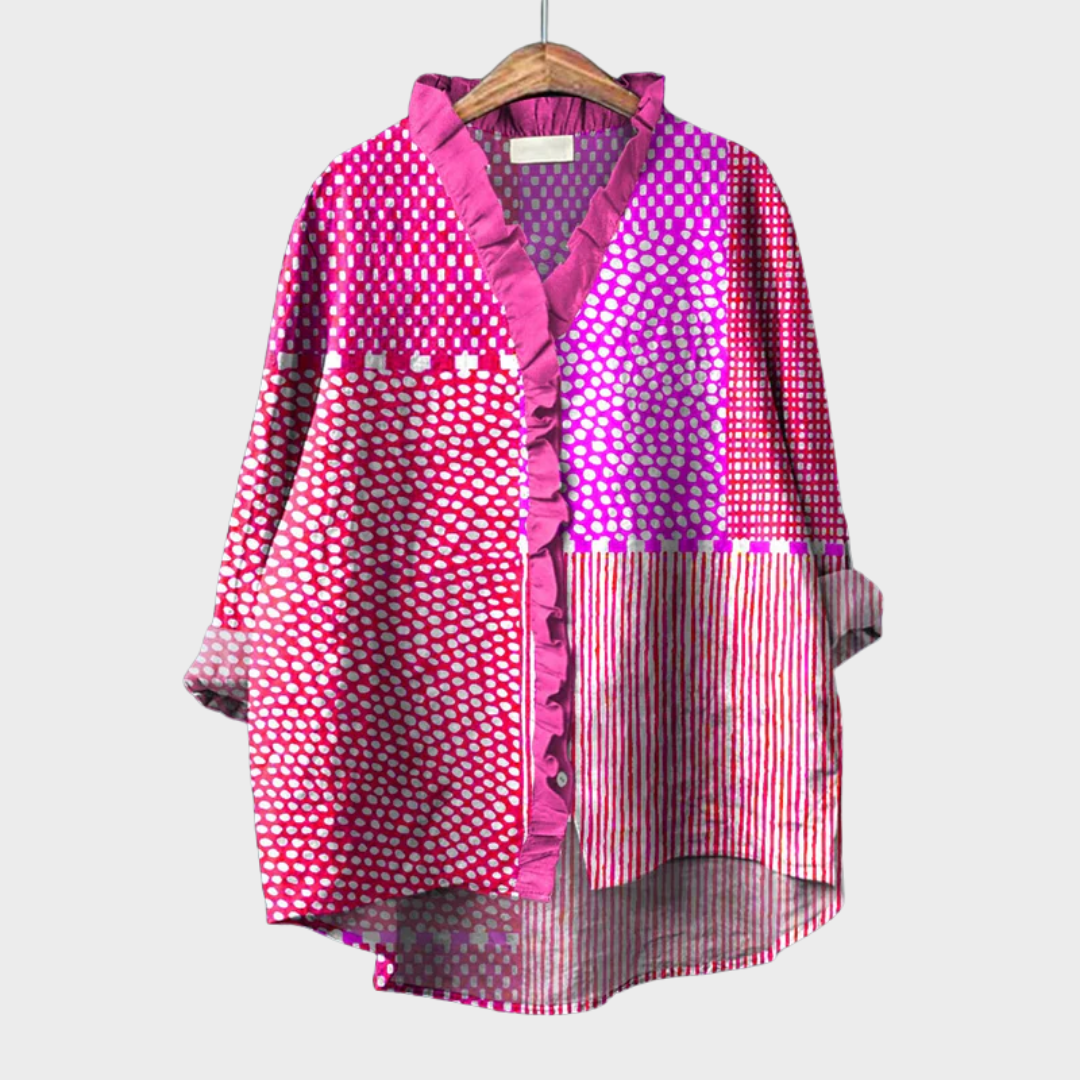 A woman wearing an elegant pink-violet patterned summer blouse, looking relaxed and polished on a warm day.