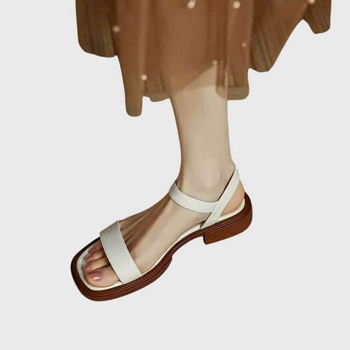 A woman in white square-toe ankle-strap sandals dressed for a summer brunch.