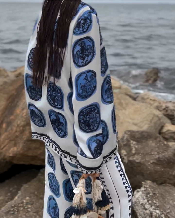 A woman wearing a blue-and-white printed open-collar shirt and matching straight-leg pants on a warm summer day