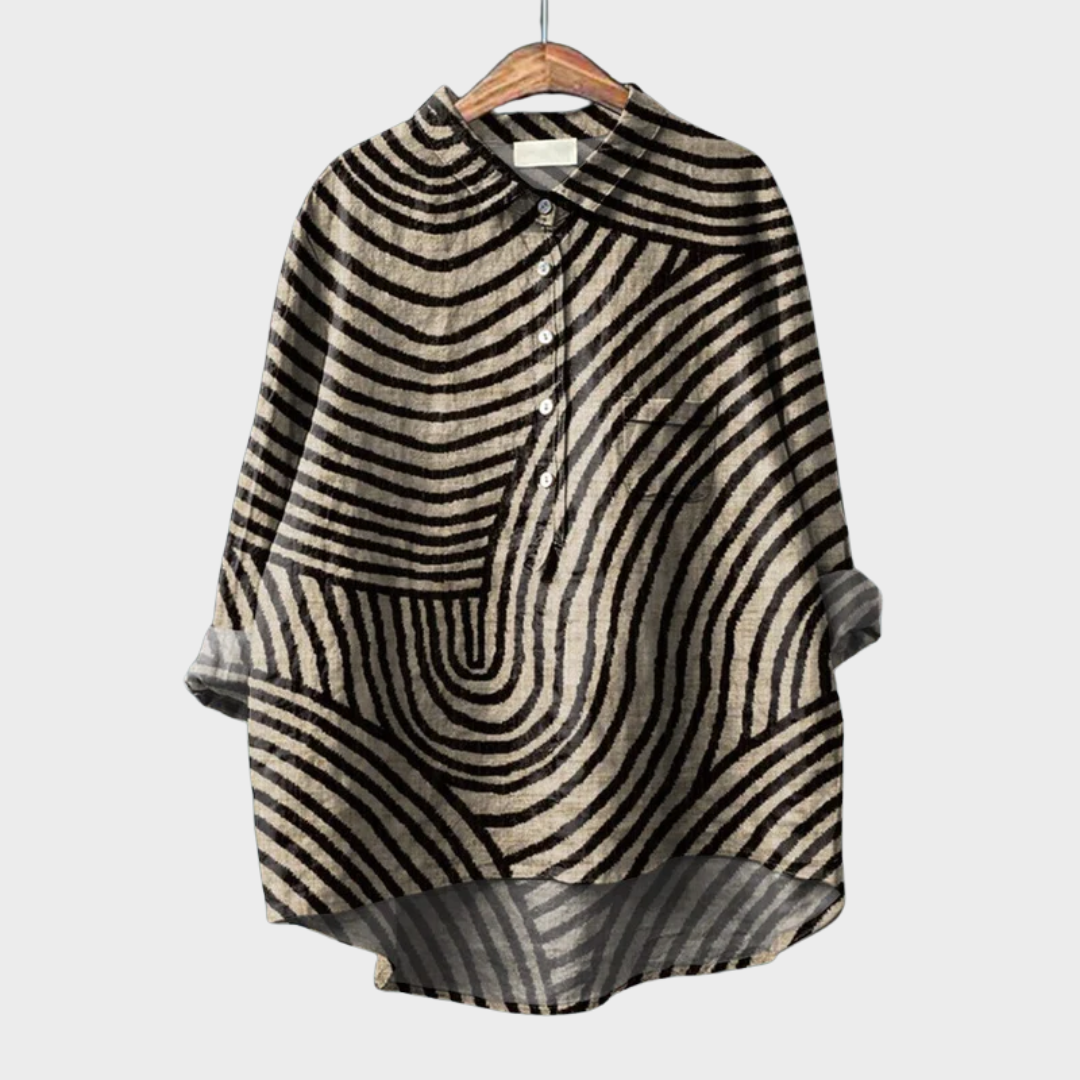 A woman wearing a beige summer blouse with a black wavy line print, looking polished and at ease on a warm day.