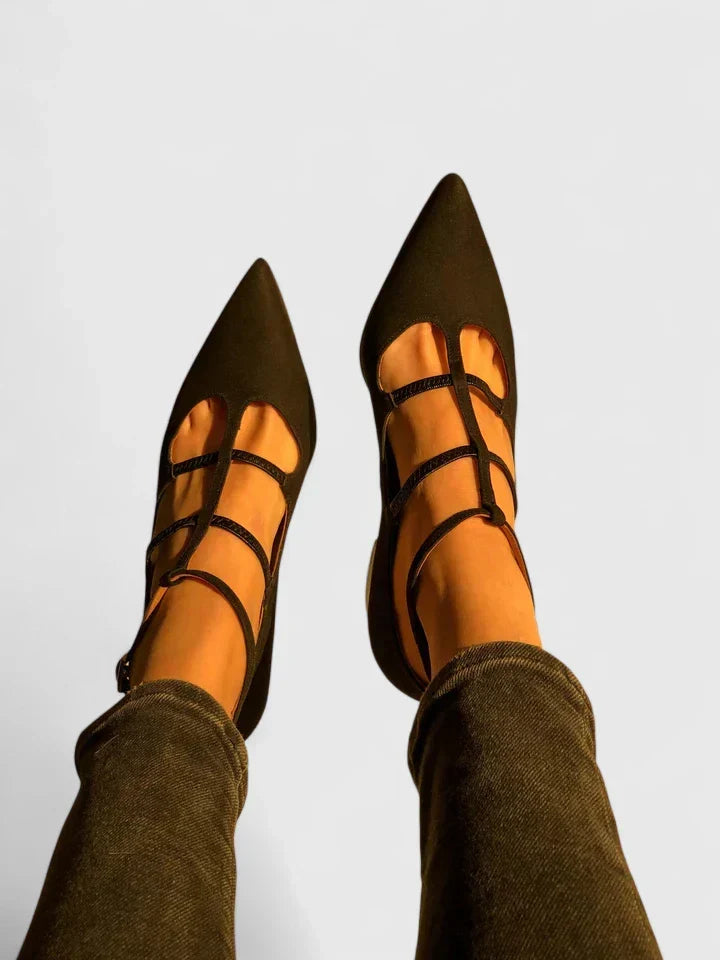 A woman walking through the city in black pointed-toe block heels with slim ankle straps, relaxed and confident.