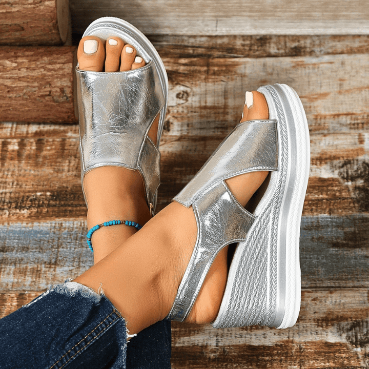 A woman wearing gold metallic sandals with a cushioned insole and wide, supportive fit.