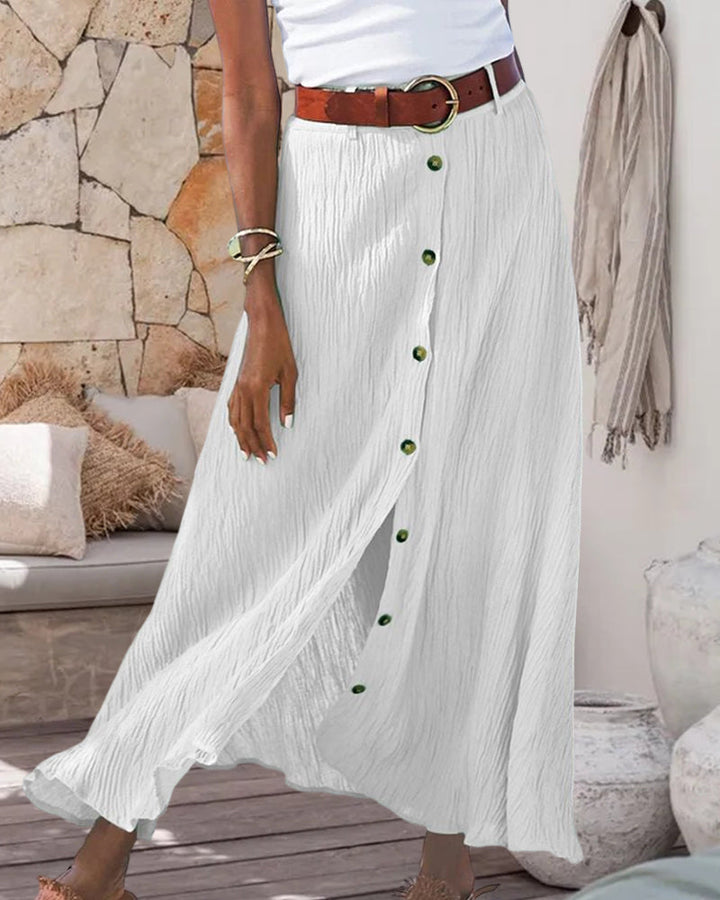 Woman wearing a flowing high-waisted button skirt with a tucked-in top, walking outdoors.