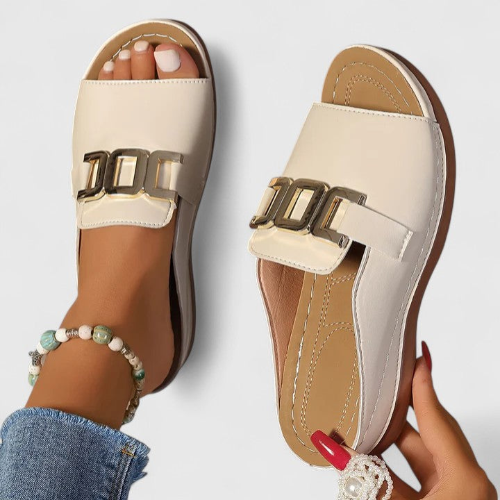 A woman wearing white comfort slides with a golden front trim and a cushioned sole.