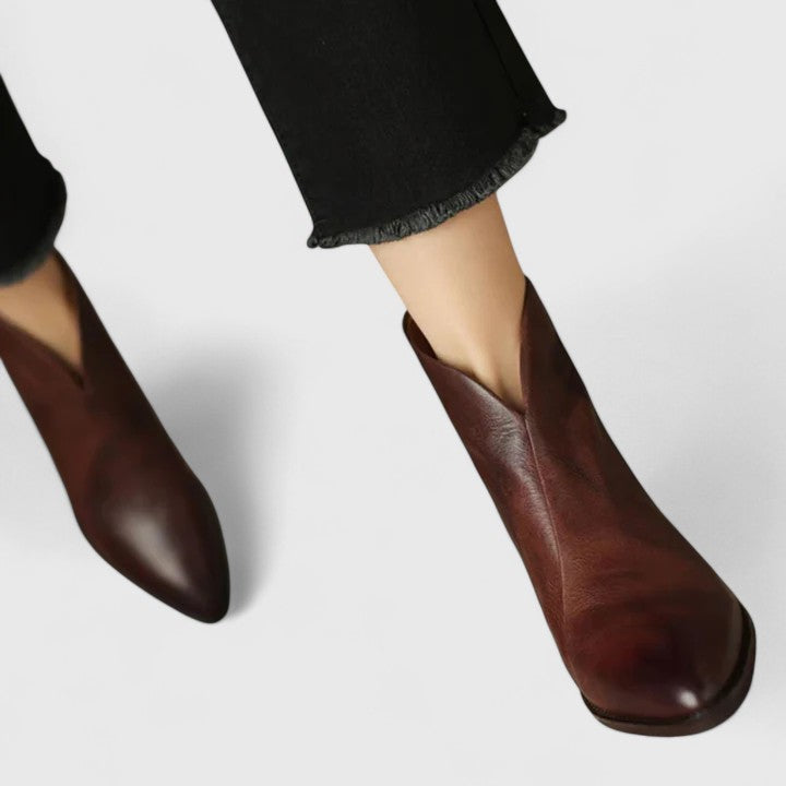 Woman wearing black elegant boots with tailored pants on a city footpath.