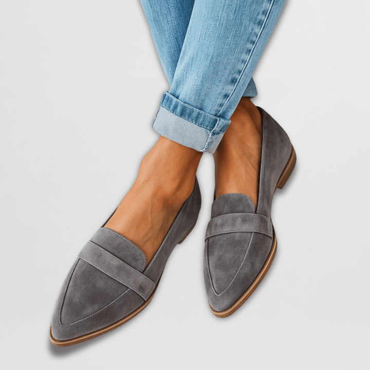 A woman wearing warm tan pointed-toe loafers with cuffed cropped jeans.