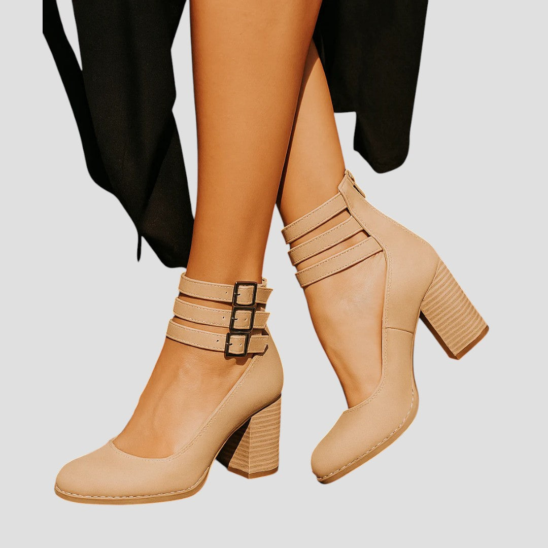 A woman wearing cognac block-heel pumps with triple ankle straps and a rounded toe.