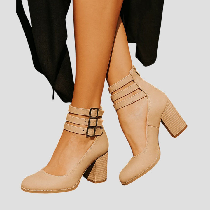 A woman wearing cognac block-heel pumps with triple ankle straps and a rounded toe.