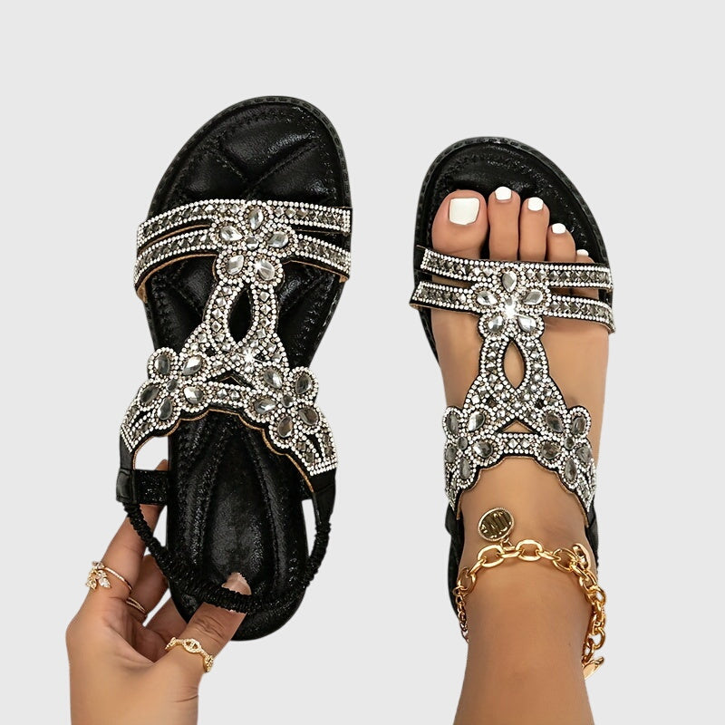 A woman wearing sky blue jewelled sandals with sparkling stones across the straps and a stretchy slingback.