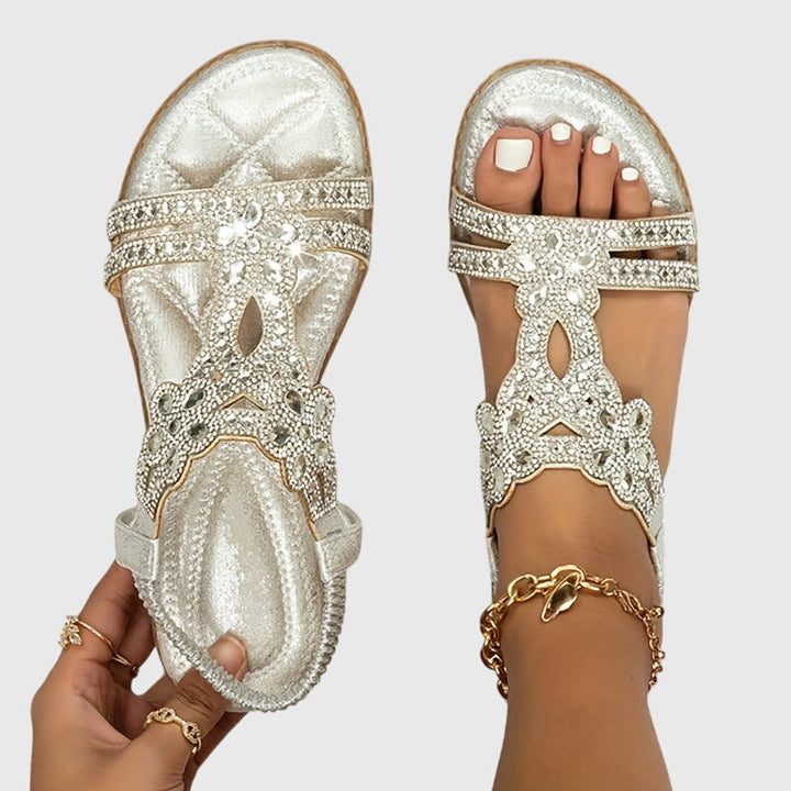 A woman wearing sky blue jewelled sandals with sparkling stones across the straps and a stretchy slingback.