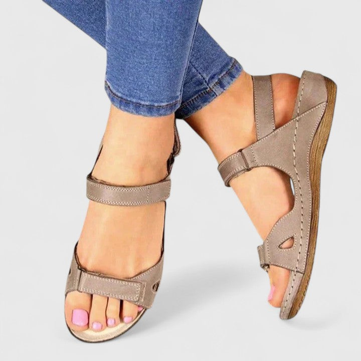 A woman walking through town in tan flat comfort sandals, relaxed and at ease.