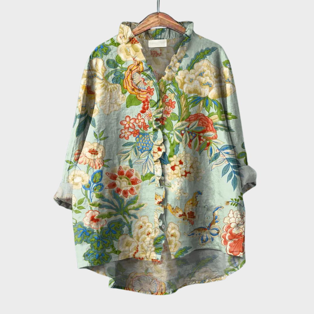 A woman wearing an elegant green floral summer blouse, looking relaxed and polished on a warm day.