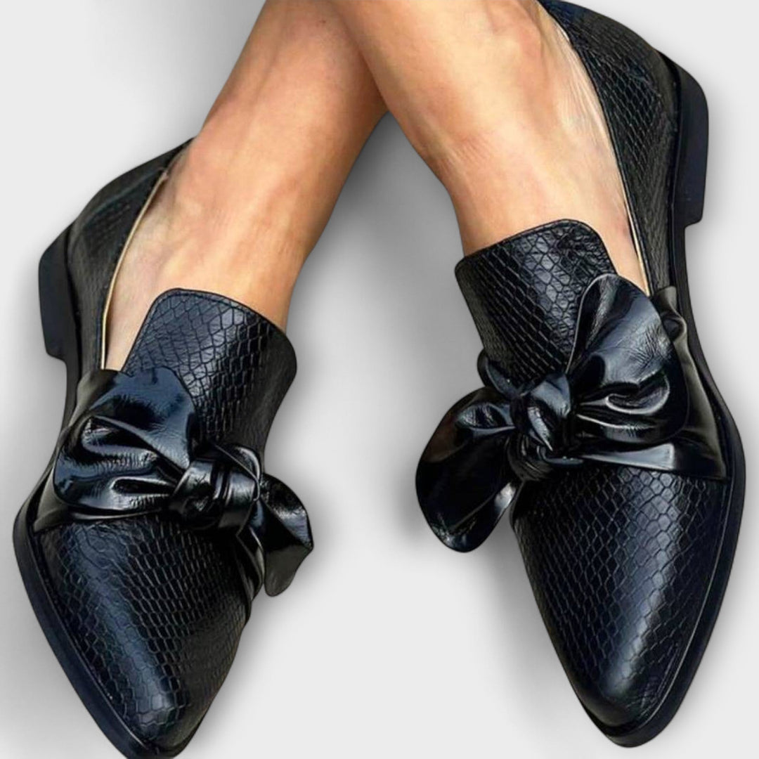 A woman wearing slip-on loafers with a delicate bow detail, styled for a relaxed day out.
