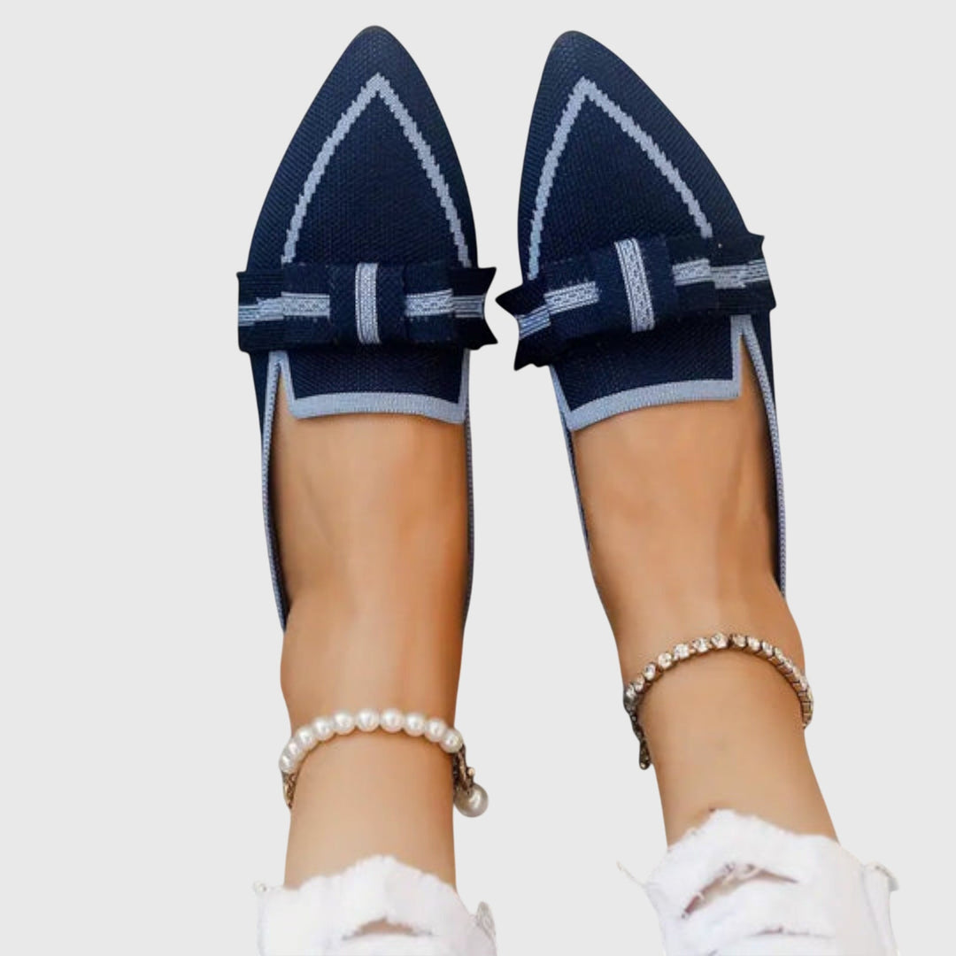 A woman wearing black flat loafers with a chic bow detail, styled for an easy day out.