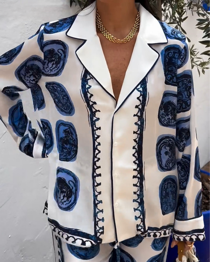 A woman wearing a blue-and-white printed open-collar shirt and matching straight-leg pants on a warm summer day