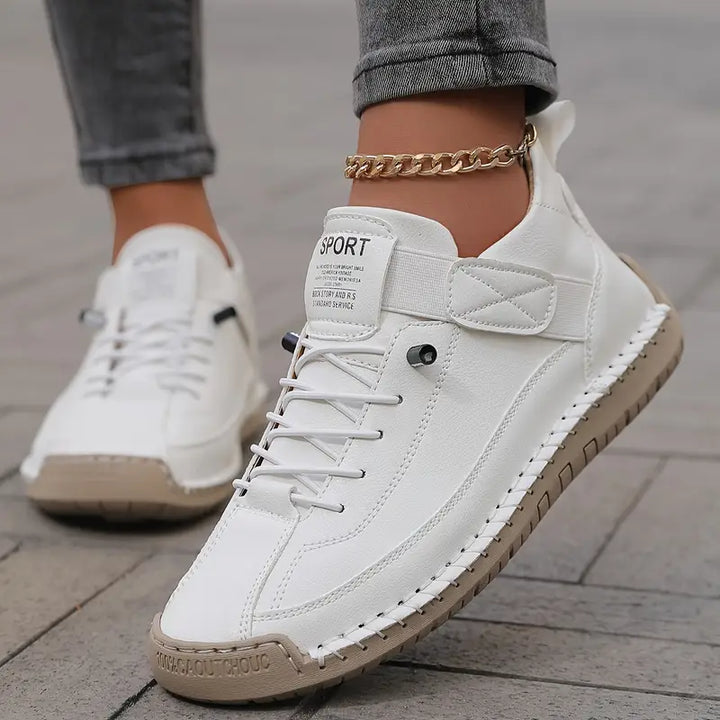 A woman wearing white lace-up orthopaedic sneakers with an adjustable strap.