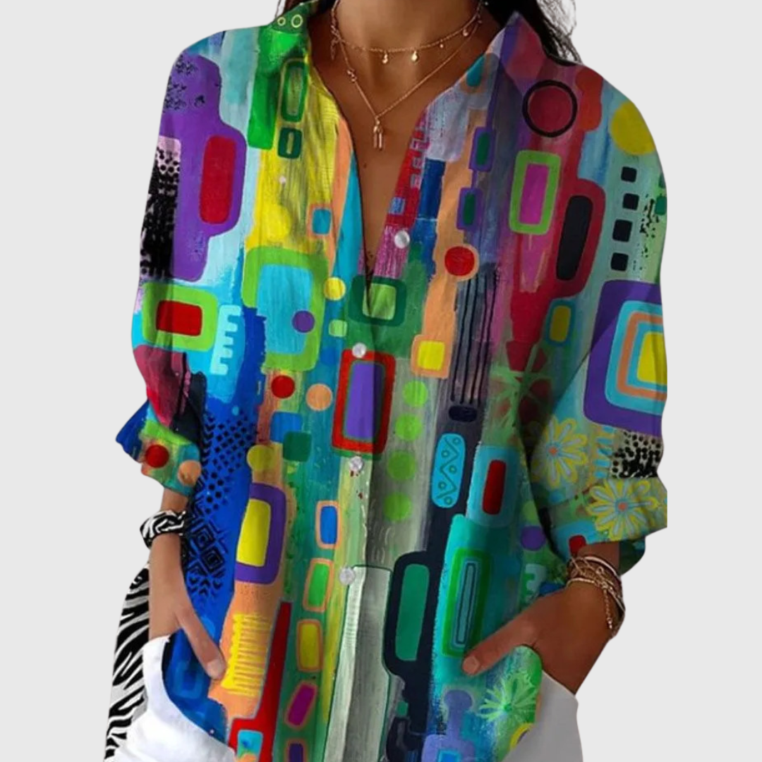 A woman wearing a flowing colourful printed blouse with an elegant button front, relaxed and comfortable on a bright day out.