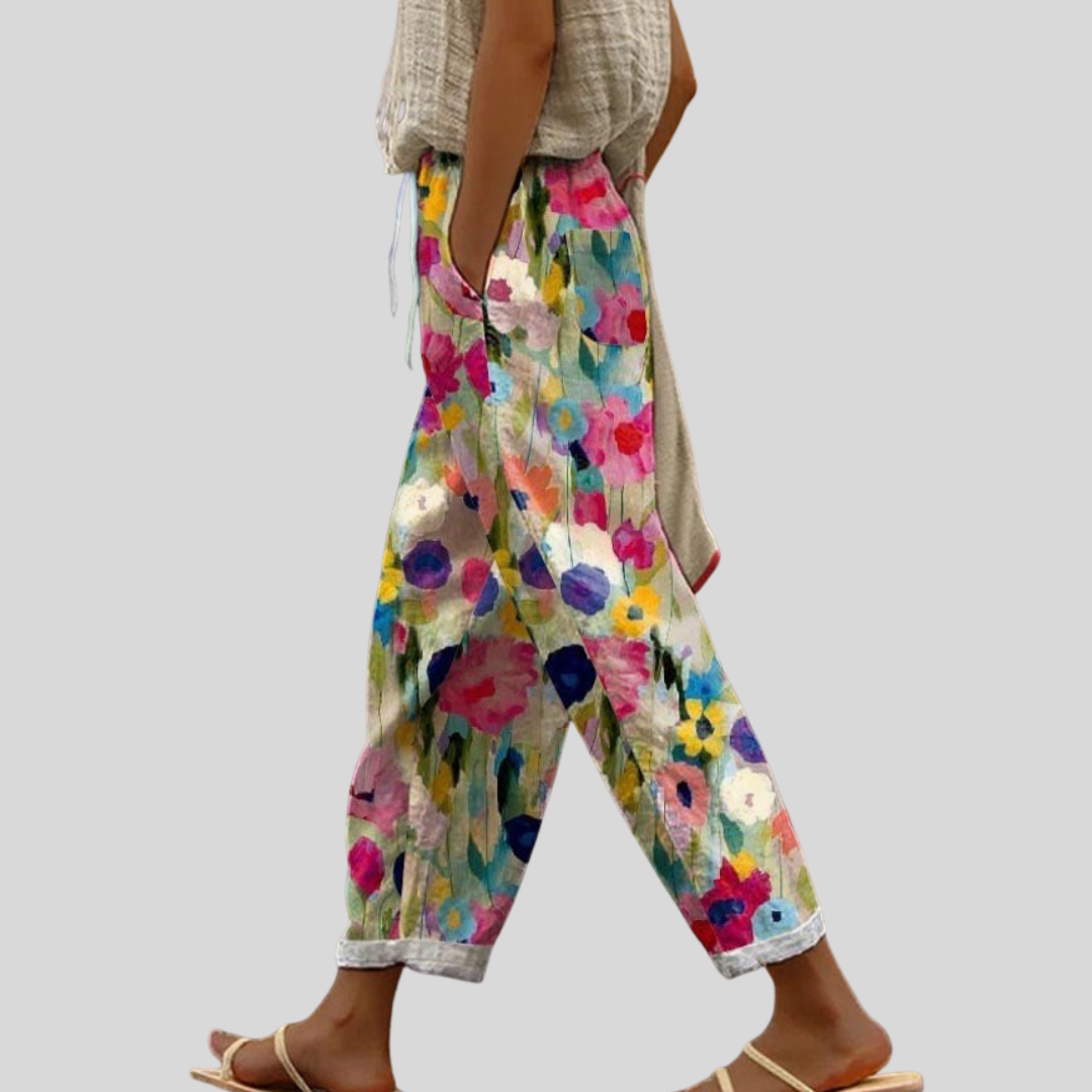 Woman wearing relaxed pants with a bright painted floral print in pink, blue and yellow.