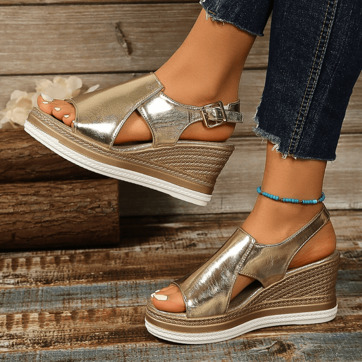 A woman wearing gold metallic sandals with a cushioned insole and wide, supportive fit.