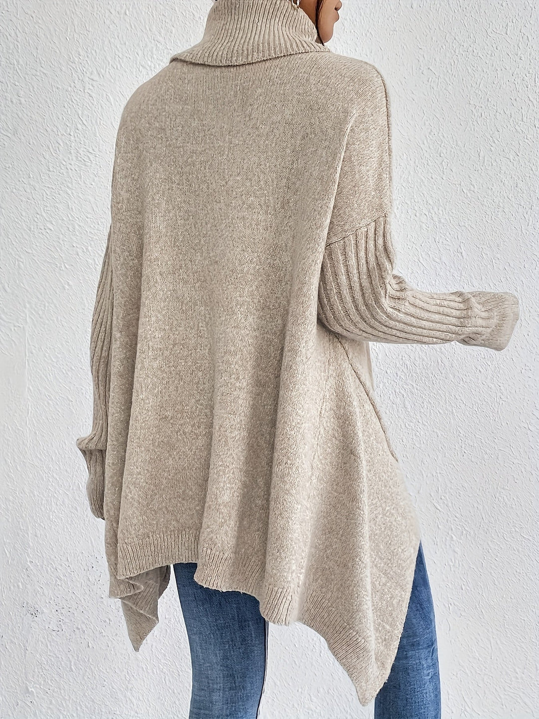 A woman wearing a stand-collar sweater with a chic asymmetric drape, warm and polished.