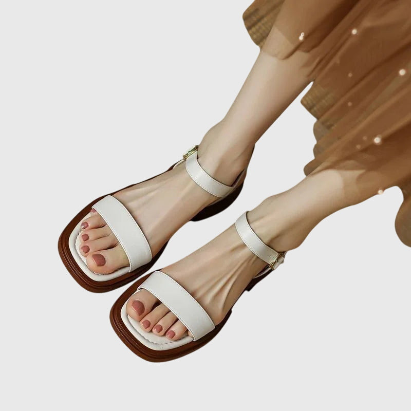 A woman in white square-toe ankle-strap sandals dressed for a summer brunch.