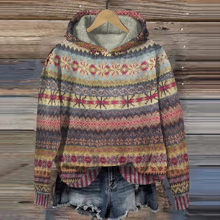 A woman wearing a retro hooded sweater in warm tones with a colourful Nordic pattern.
