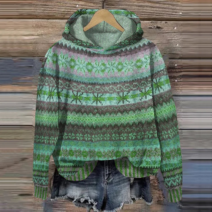 A woman wearing a retro hooded sweater in warm tones with a colourful Nordic pattern.