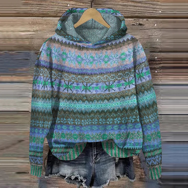 A woman wearing a retro hooded sweater in warm tones with a colourful Nordic pattern.