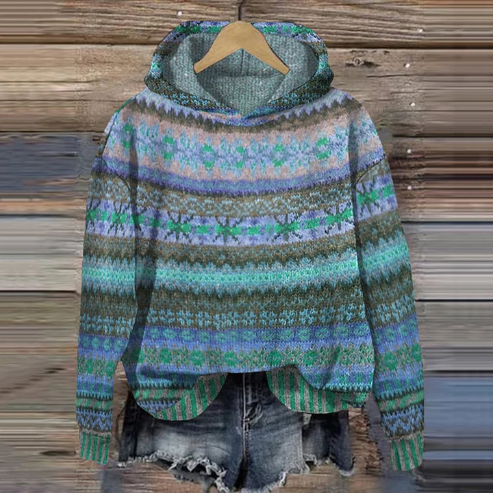 A woman wearing a retro hooded sweater in warm tones with a colourful Nordic pattern.