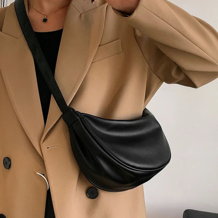 A woman carrying a black crescent-shaped shoulder bag with an adjustable strap