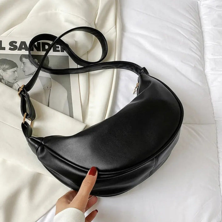A woman carrying a black crescent-shaped shoulder bag with an adjustable strap