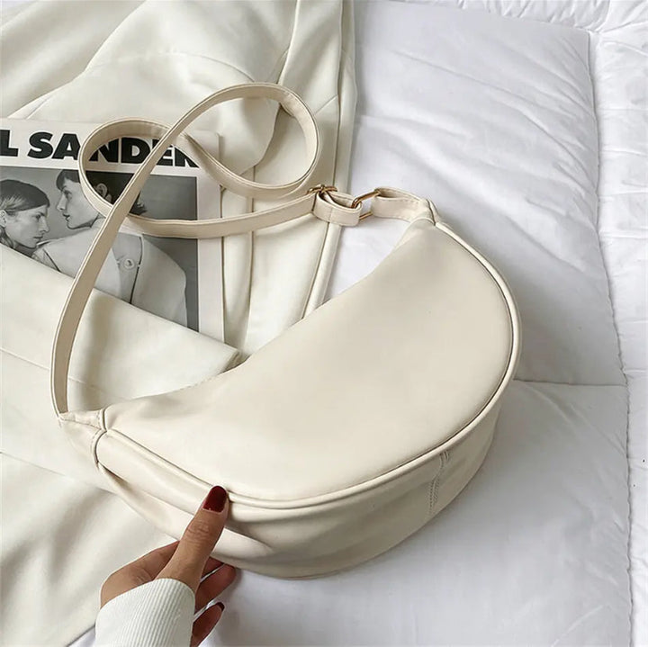 A woman carrying a black crescent-shaped shoulder bag with an adjustable strap