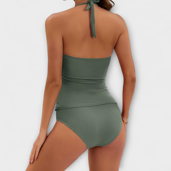 A woman by the water in a solid-colour two-piece halter swimsuit, relaxed and confident in the sun.