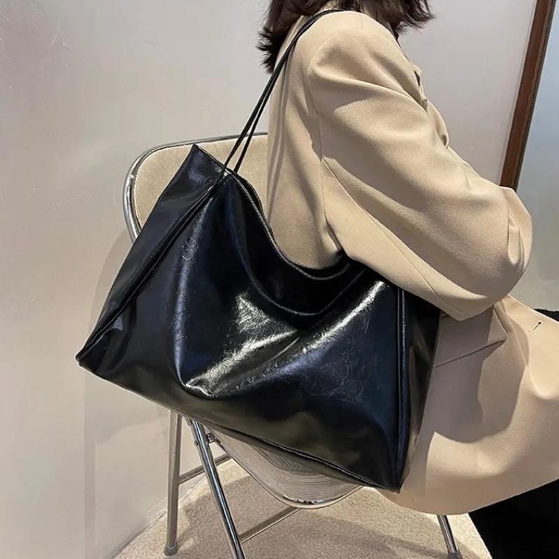 A woman wearing a glossy taupe shoulder bag over her shoulder at an evening occasion.