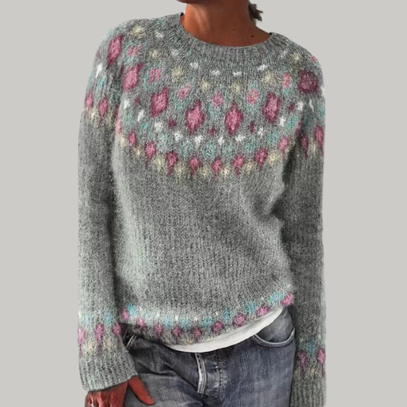 A woman wearing a grey round-neck sweater with a colourful Nordic patterned yoke.