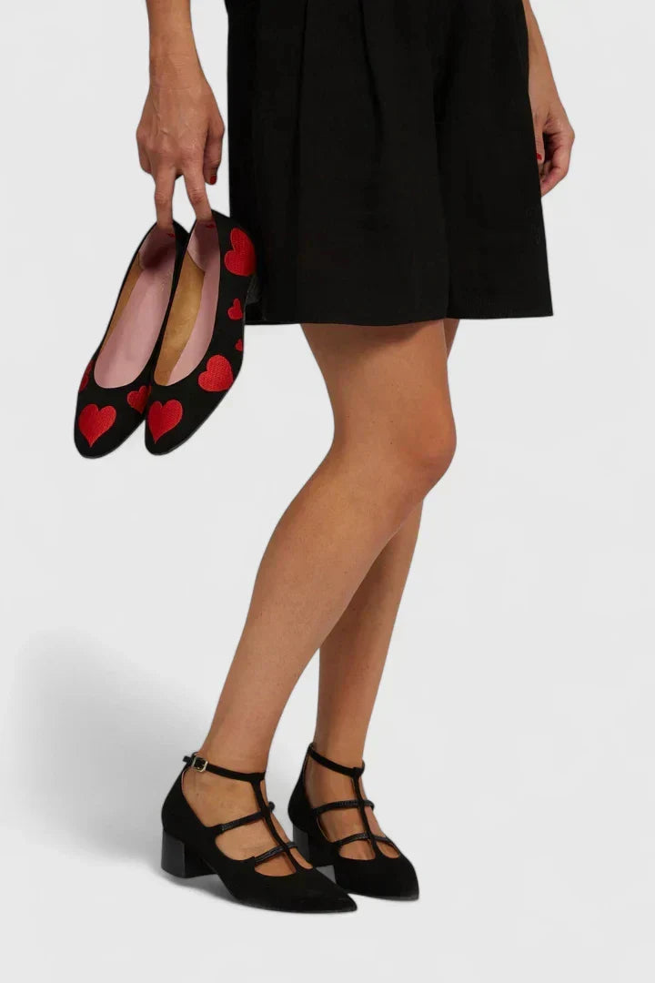 A woman walking through the city in black pointed-toe block heels with slim ankle straps, relaxed and confident.