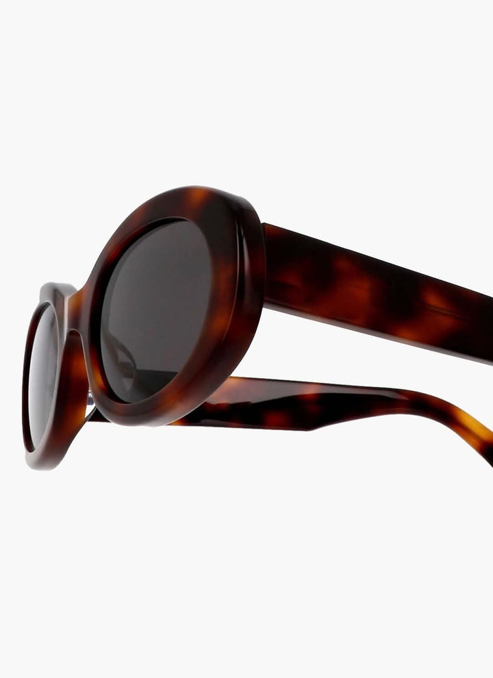 A woman wearing retro oval vintage sunglasses on a sunny day out.