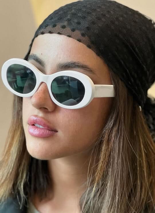 A woman wearing retro oval vintage sunglasses on a sunny day out.