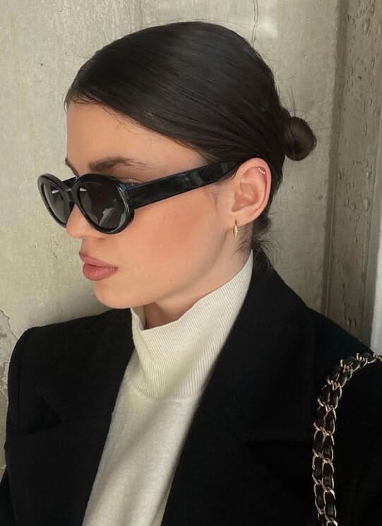 A woman wearing retro oval vintage sunglasses on a sunny day out.