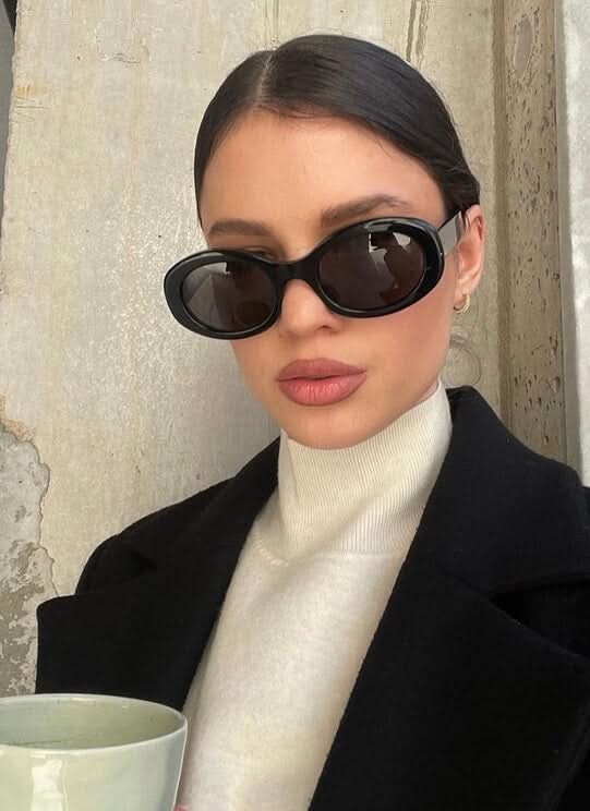 A woman wearing retro oval vintage sunglasses on a sunny day out.