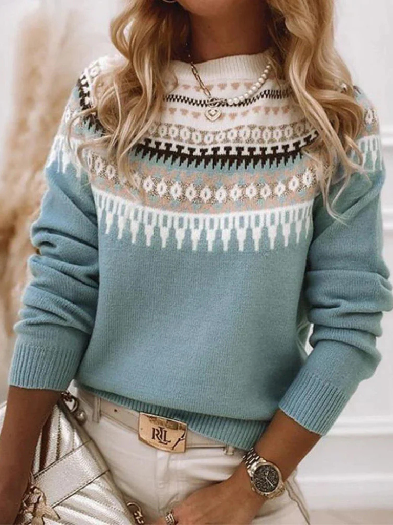 A woman wearing a soft powder-blue sweater with a cream, tan and black Nordic yoke pattern