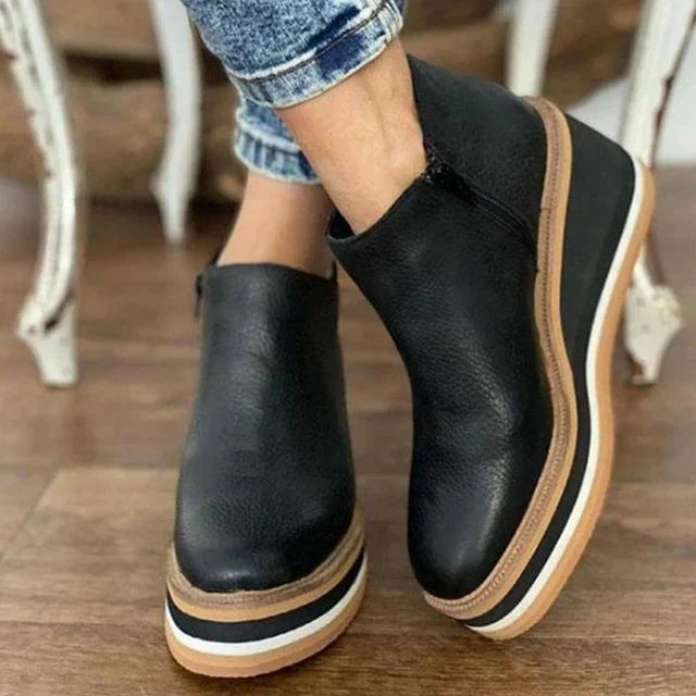 A woman wearing sleek minimalist ankle boots with jeans on a city break.